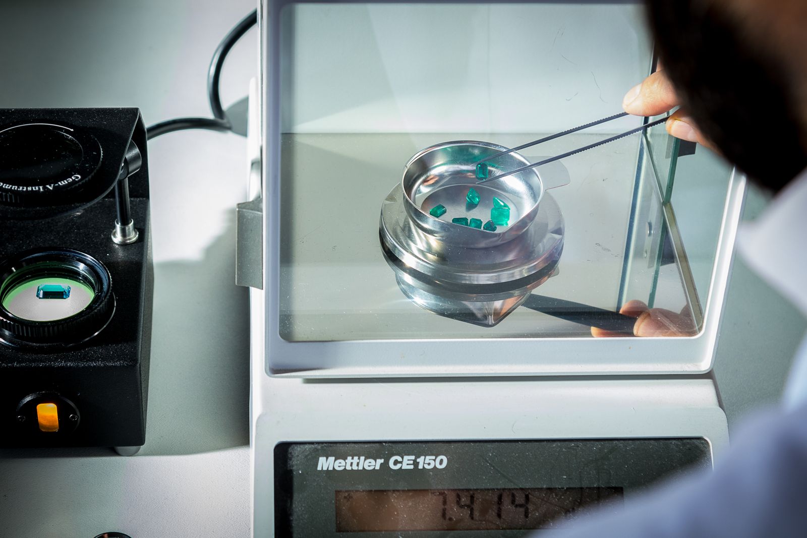 Emerald-cut stones being weighed on a Mettler precision balance with tweezers